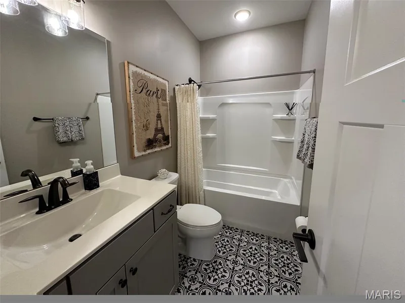 Bathroom featuring a patterned tile floor, a vanity with an integrated sink, a dark bronze faucet, and a shower/tub combination with built-in shelving — 110 Alta Mira Court, Dardenne Prairie, MO 63368