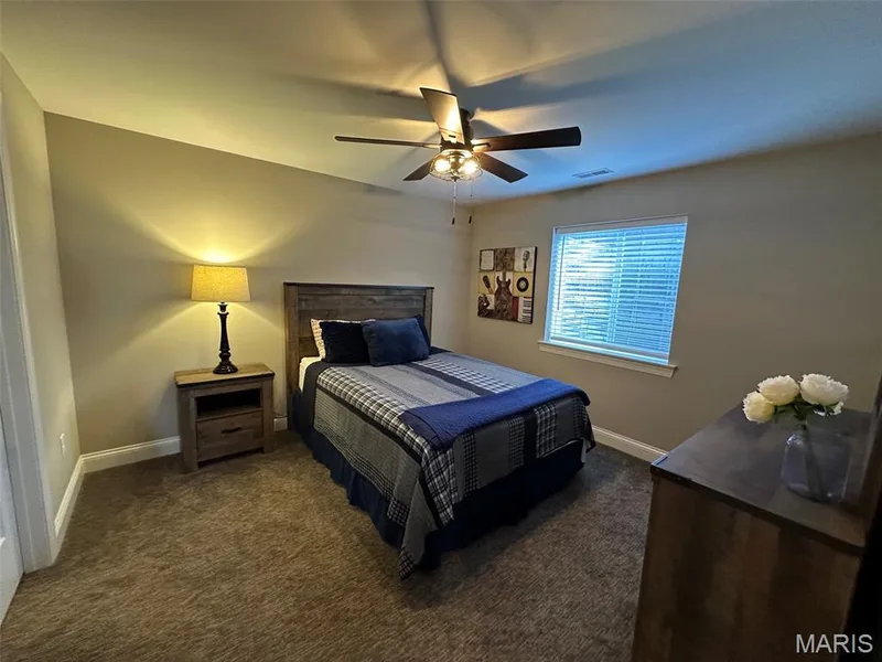 Carpeted bedroom featuring a ceiling fan with integrated lighting, a window with blinds, and white baseboards — 110 Alta Mira Court, Dardenne Prairie, MO 63368