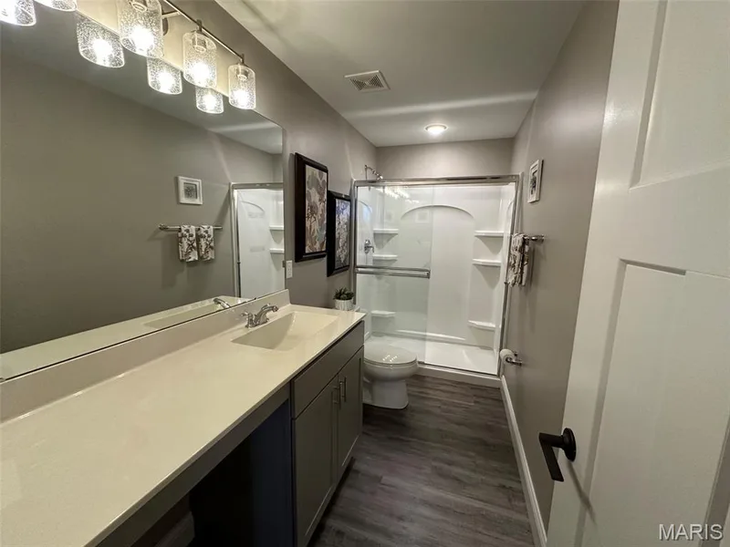 Bathroom featuring an extended single vanity with an integrated sink, a large wall mirror, and a track light fixture — 110 Alta Mira Court, Dardenne Prairie, MO 63368