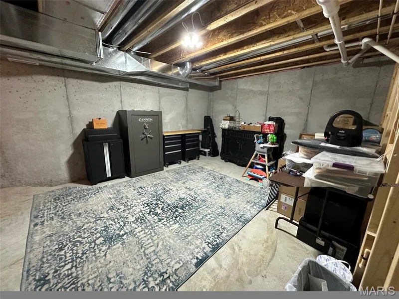 Unfinished basement space featuring exposed concrete walls, visible ceiling joists, and overhead utility lines — 110 Alta Mira Court, Dardenne Prairie, MO 63368