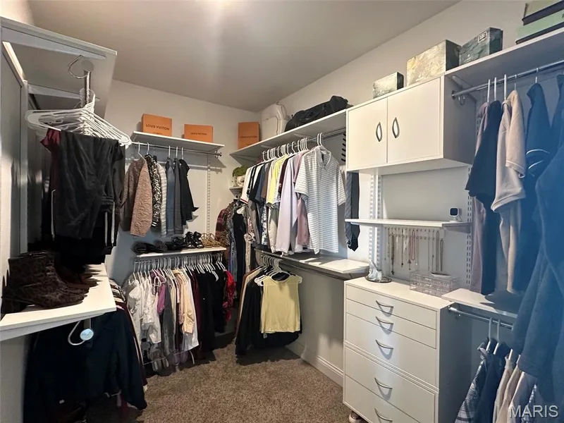 Walk-in closet featuring built-in white shelving, hanging rods, and a multi-drawer dresser — 110 Alta Mira Court, Dardenne Prairie, MO 63368