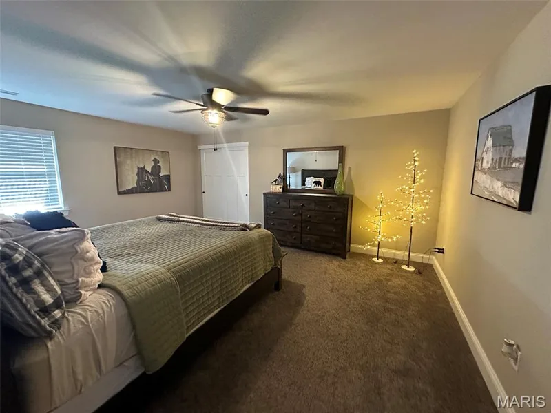 Carpeted room featuring a ceiling fan with integrated lighting, a window with horizontal blinds, a paneled door, and neutral-toned walls — 110 Alta Mira Court, Dardenne Prairie, MO 63368
