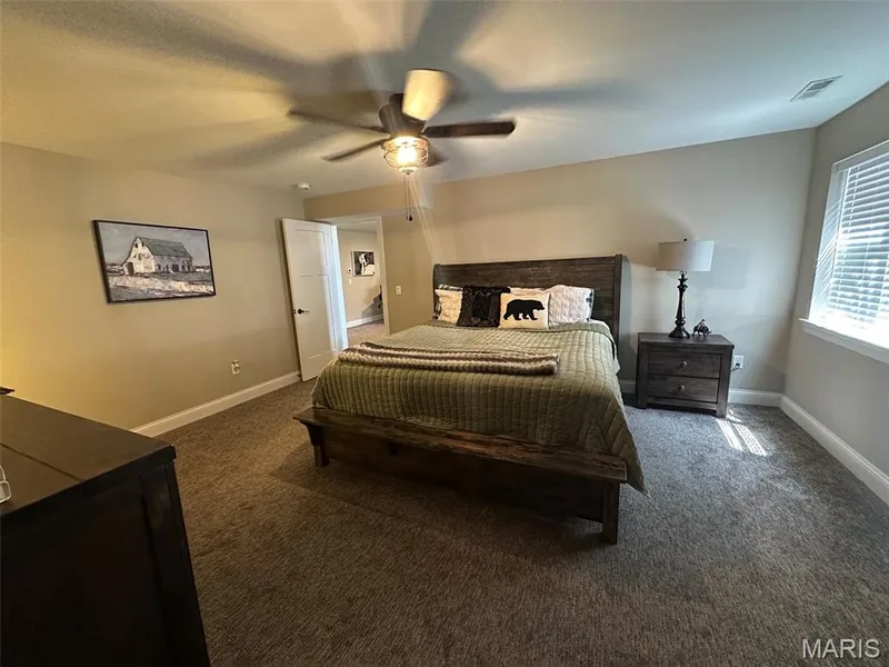 Bedroom featuring neutral-toned carpet, a ceiling fan with integrated lighting, and a white interior door — 110 Alta Mira Court, Dardenne Prairie, MO 63368