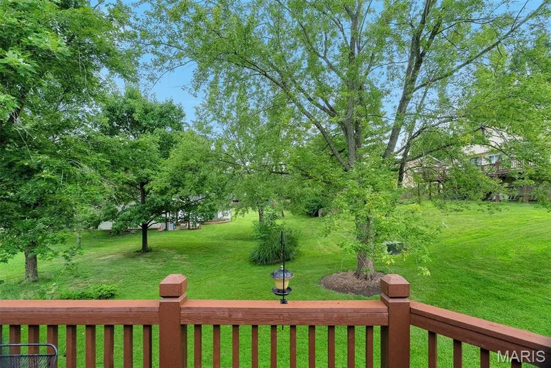 Expansive backyard oasis featuring a manicured lawn, mature shade trees, and a freshly stained and updated wood decking — 104 Cedar Crest Court, St Charles, MO 63304
