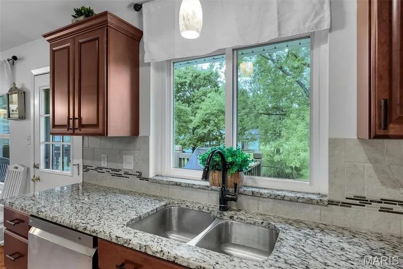 Undermount double basin stainless steel sink with a matte black gooseneck faucet, set within a speckled countertop — 104 Cedar Crest Court, St Charles, MO 63304