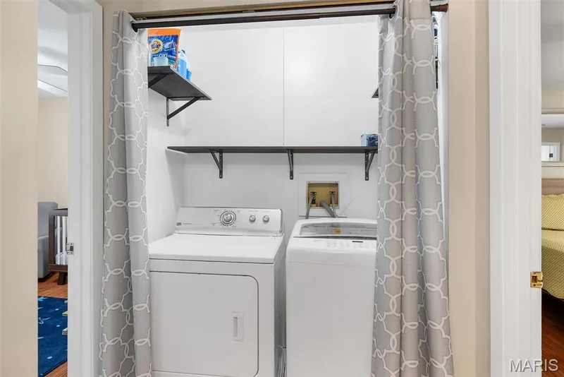 Dedicated laundry located at end of hall between 3 bedrooms.  Closet featuring a stacked washer and dryer, built-in shelving, and a hanging rod for air-drying garments — 104 Cedar Crest Court, St Charles, MO 63304