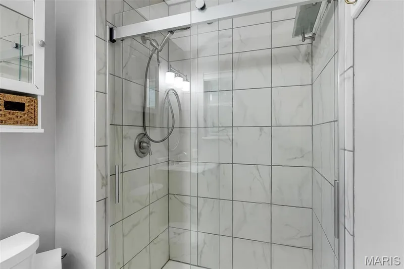Modern bathroom featuring a frameless glass shower enclosure with polished chrome hardware, subway tile surround with linear grout lines, and a rainfall showerhead — 104 Cedar Crest Court, St Charles, MO 63304