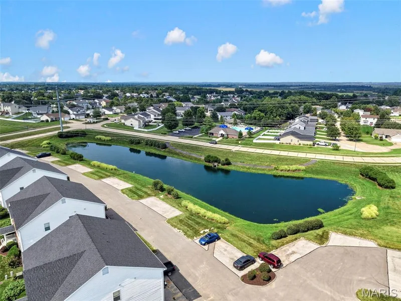 Community with a pond, surrounding green spaces, and paved parking — 669 Homerun Drive, O'Fallon, MO 63366
