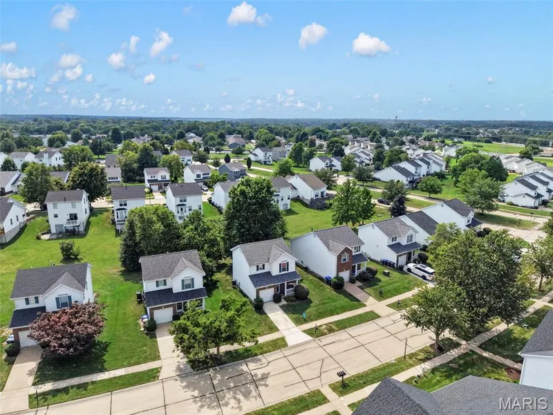 Aerial perspective of a residential neighborhood with detached homes, mature trees, and paved streets — 669 Homerun Drive, O'Fallon, MO 63366