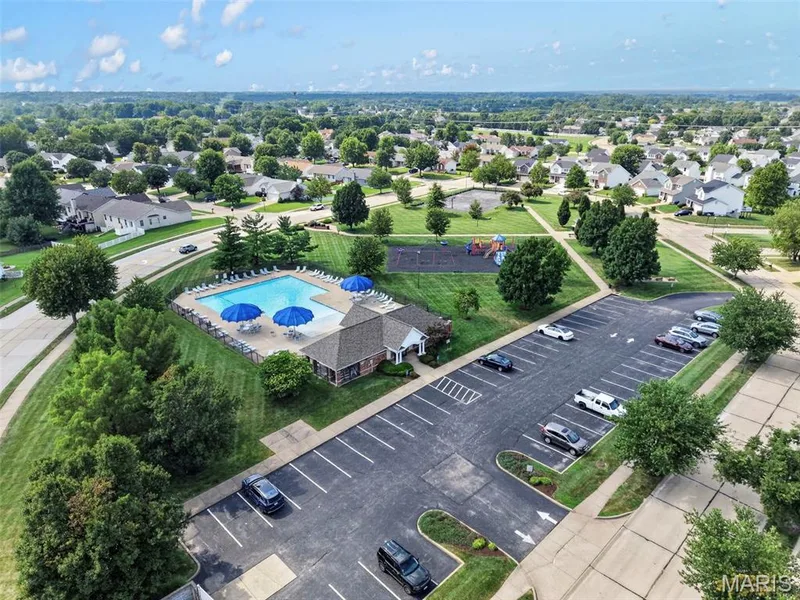 Community amenities featuring a swimming pool, clubhouse, playground, and paved parking — 669 Homerun Drive, O'Fallon, MO 63366