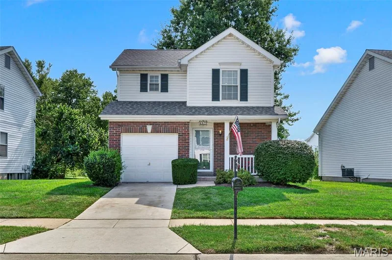 Two-story exterior with brick and siding facade, featuring a single-car garage and a covered front porch — 669 Homerun Drive, O'Fallon, MO 63366