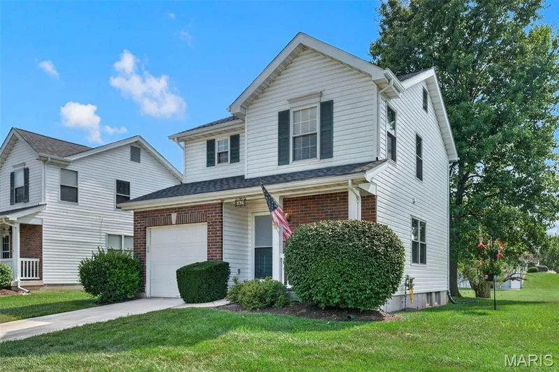 White siding exterior with a brick facade, attached garage, and dark window shutters — 669 Homerun Drive, O'Fallon, MO 63366