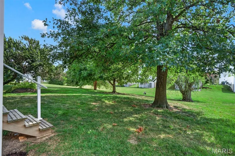 Expansive green lawn with mature trees providing natural shading — 669 Homerun Drive, O'Fallon, MO 63366