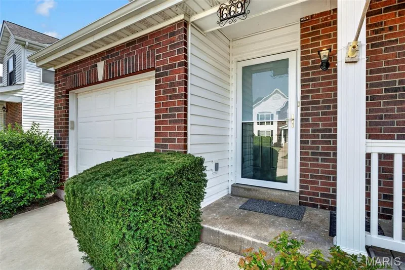 Brick and siding exterior with an attached single-car garage, a storm door, and a covered porch entry — 669 Homerun Drive, O'Fallon, MO 63366