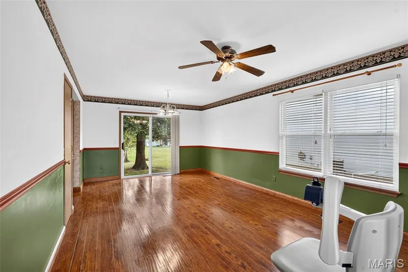 Wood-finish flooring, ceiling fan with integrated lighting, double-pane windows with blinds, sliding glass door, and a multi-light chandelier — 669 Homerun Drive, O'Fallon, MO 63366