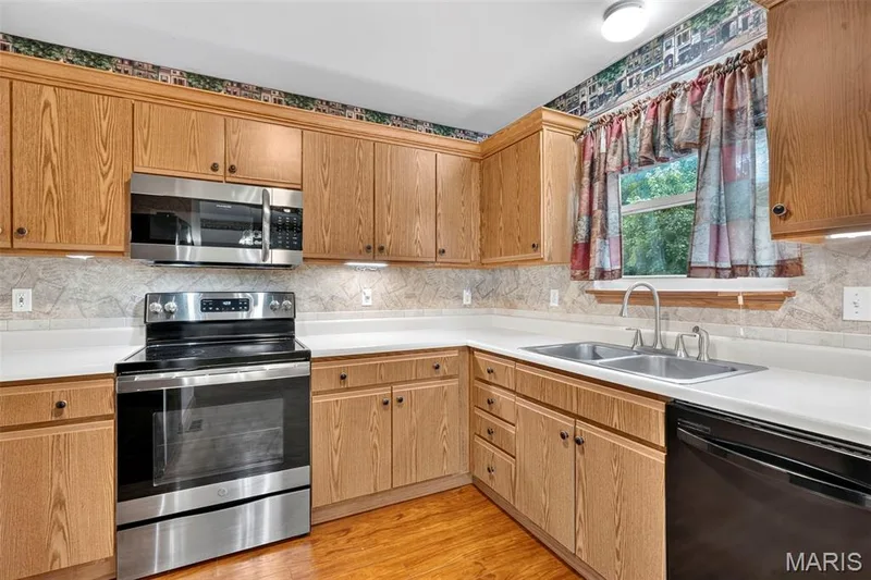 Wood-finish cabinetry, stainless steel appliances, and a double basin sink — 669 Homerun Drive, O'Fallon, MO 63366