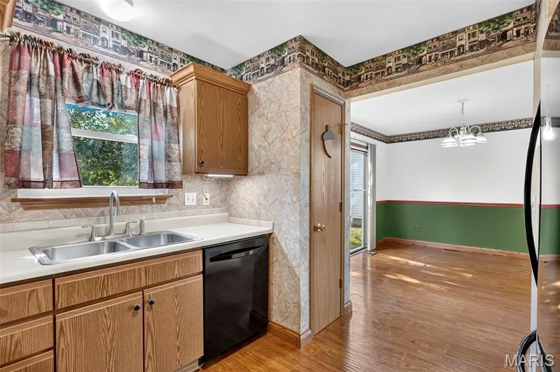 Kitchen featuring a double basin stainless steel sink, wood-finish cabinetry, and black dishwasher — 669 Homerun Drive, O'Fallon, MO 63366
