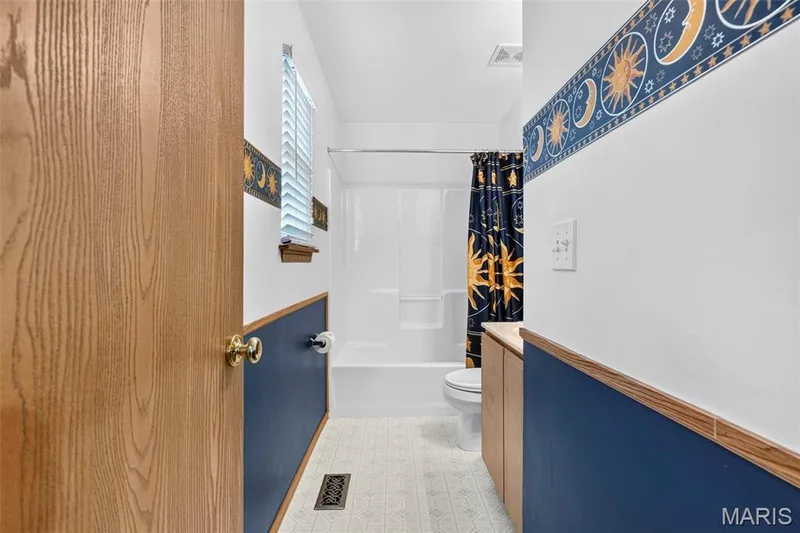 Bathroom featuring a white bathtub, wood-finish vanity, and a window with blinds — 669 Homerun Drive, O'Fallon, MO 63366