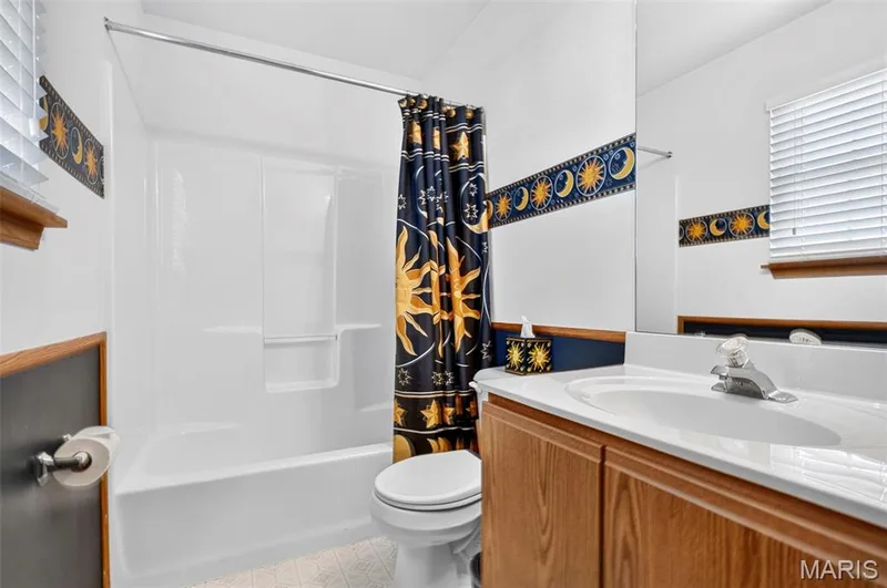 White bathtub with an integrated shower, white vanity countertop, and wood-finish cabinetry — 669 Homerun Drive, O'Fallon, MO 63366