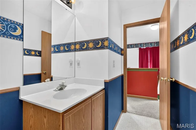 Vanity with integrated sink, wood-finish cabinetry, and wall-mounted mirror — 669 Homerun Drive, O'Fallon, MO 63366