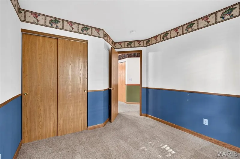 Carpeted flooring, wood-finish bi-fold closet doors, and a wood-finish door frame — 669 Homerun Drive, O'Fallon, MO 63366