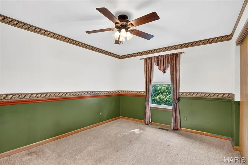 Ceiling fan with light fixture, carpeted flooring, wall trim, window, and two-tone wall paint — 669 Homerun Drive, O'Fallon, MO 63366