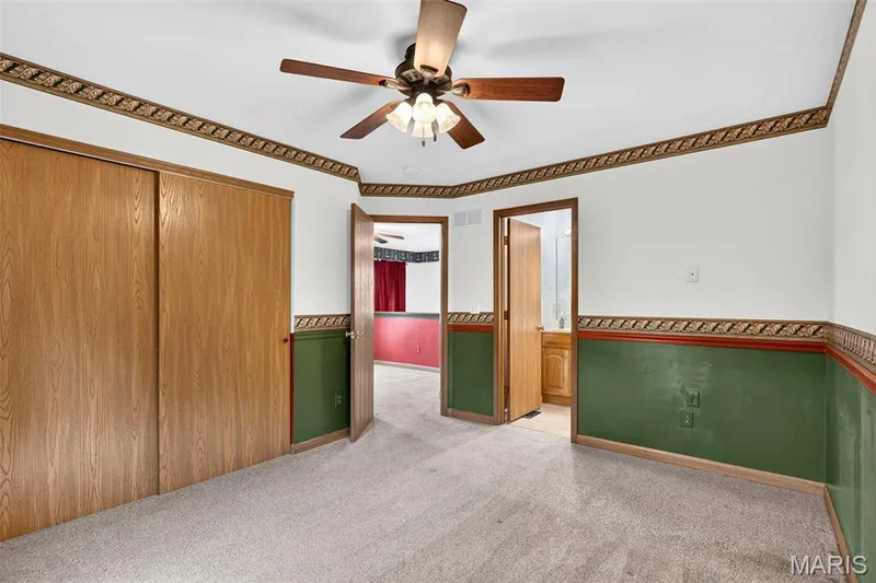 Neutral-toned carpeting, ceiling fan with integrated lighting, wood-finish bi-fold closet doors, and wood-finish interior doors — 669 Homerun Drive, O'Fallon, MO 63366