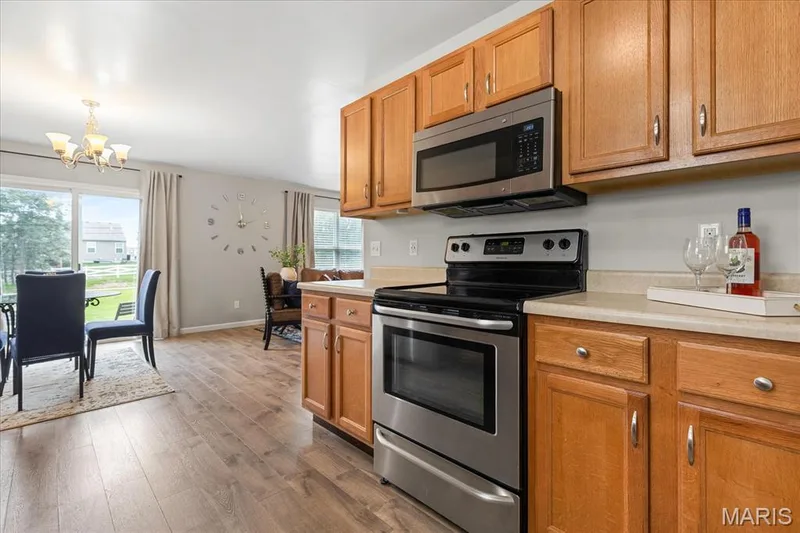 Another view of the kitchen where modern stainless appliances and warm wood cabinetry combine to create an inviting, practical space. — 146 Tuscany Lane, Wentzville, MO 63385