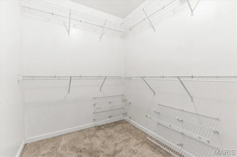 Oversized primary walk-in closet featuring multi-tier wire shelving, angled display racks, and abundant storage space. — 146 Tuscany Lane, Wentzville, MO 63385