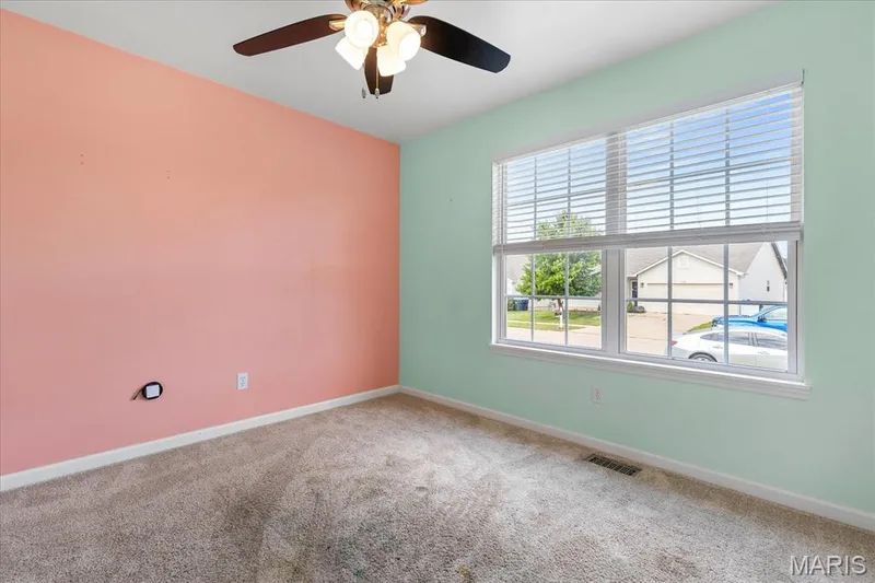 A cozy front-facing additional bedroom filled with light from the large windows, perfect for guests, a home office, or hobbies. — 146 Tuscany Lane, Wentzville, MO 63385