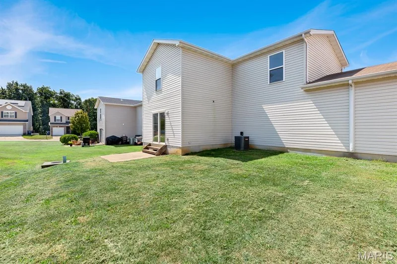 Expansive grassy yard with a concrete patio and sliding glass door access — 14 Bridgeton Court, Wentzville, MO 63385
