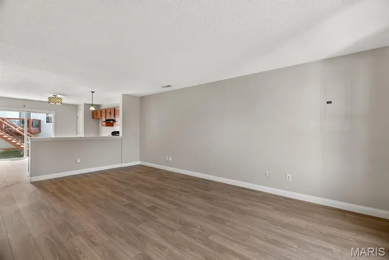 Wood-finish flooring throughout the main living area, staircase with carpeted treads, and a wall-mounted light fixture — 14 Bridgeton Court, Wentzville, MO 63385