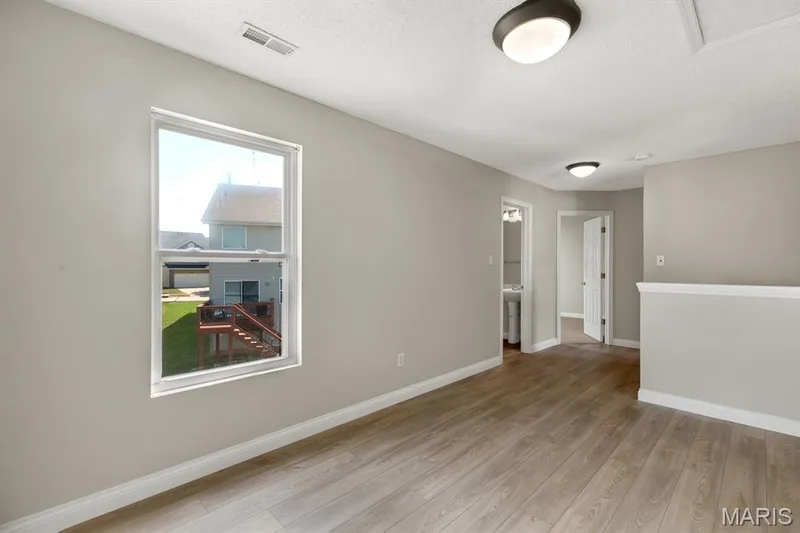 Expansive room with wood-finish flooring, neutral wall tones, and a large window — 14 Bridgeton Court, Wentzville, MO 63385