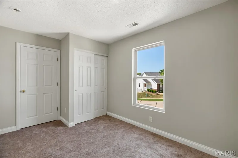 Carpeted room with a single window, a paneled door, and a two-panel sliding closet — 14 Bridgeton Court, Wentzville, MO 63385