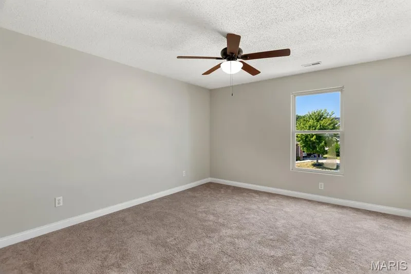 Plush carpet flooring, neutral wall tones, window with natural light, and a ceiling fan with integrated lighting — 14 Bridgeton Court, Wentzville, MO 63385