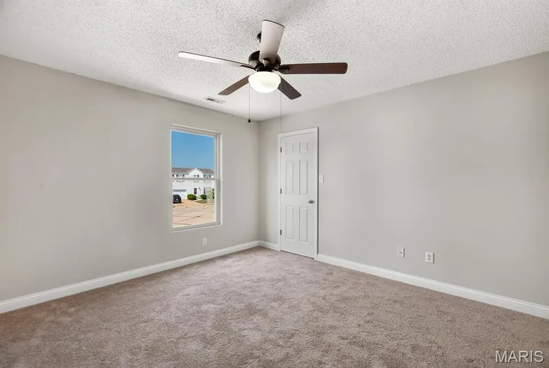Neutral wall paint, carpeting, a single window, a paneled door, and a ceiling fan with integrated lighting — 14 Bridgeton Court, Wentzville, MO 63385