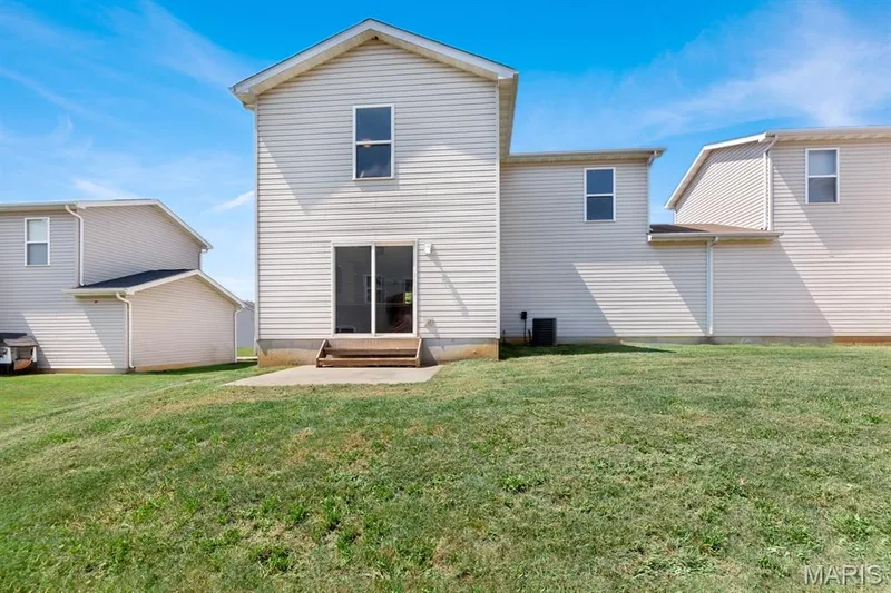 Expansive grassy yard with a concrete patio and sliding glass door access — 14 Bridgeton Court, Wentzville, MO 63385