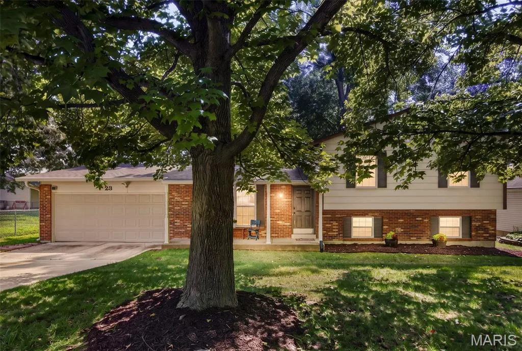 Charming brick ranch home showcasing a mature shade tree anchoring the manicured front lawn — 23 Crescent Woods Drive, St Peters, MO 63376