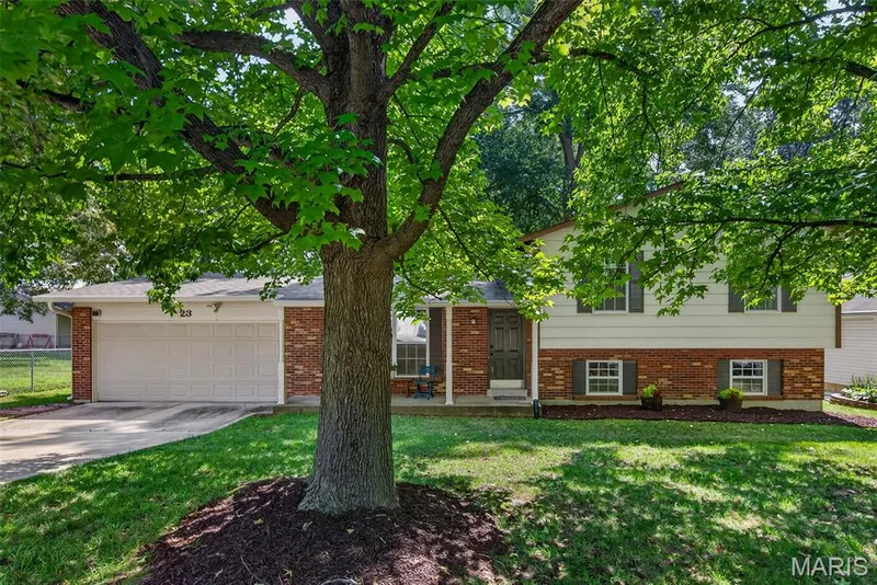 Brick ranch home with mature shade tree anchoring the front landscape — 23 Crescent Woods Drive, St Peters, MO 63376