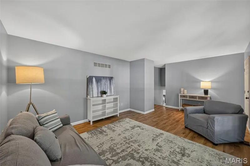 Spacious living area showcasing laminate hardwood flooring, soft gray walls — 23 Crescent Woods Drive, St Peters, MO 63376