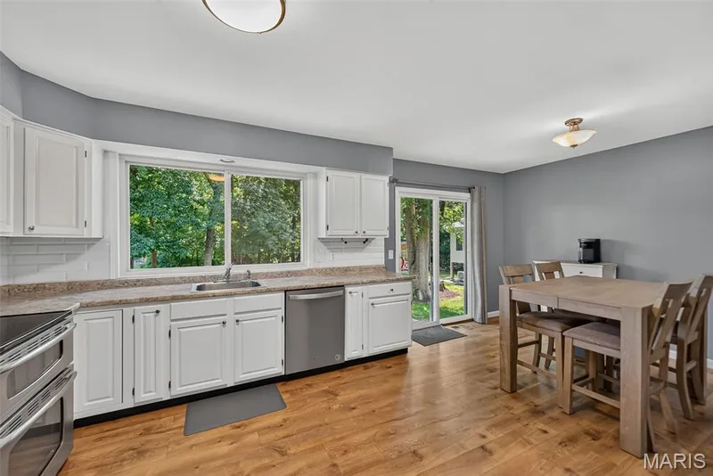 Bright and spacious kitchen featuring white cabinetry, stainless steel appliances, and a neutral countertop with undermount sink — 23 Crescent Woods Drive, St Peters, MO 63376