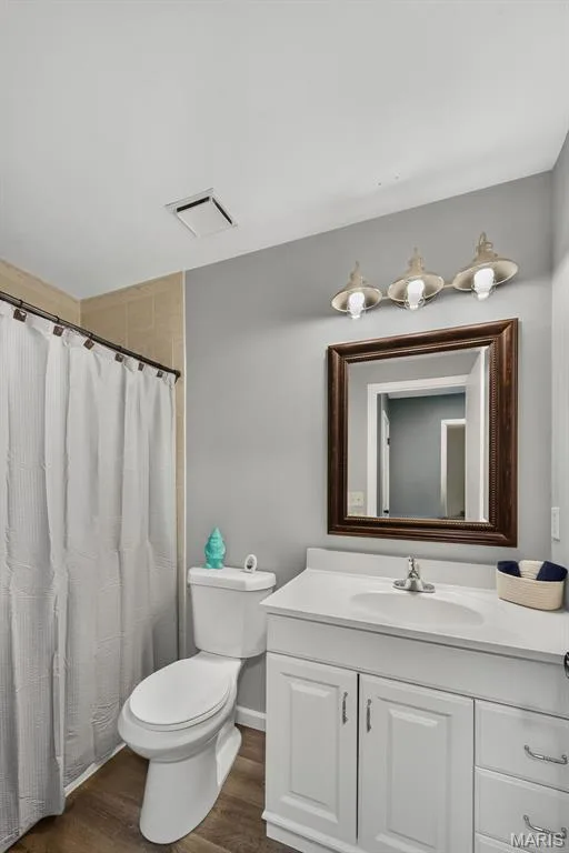 Bathroom featuring a white vanity with integrated sink, a dark wood-framed mirror, and a three-light vanity fixture — 23 Crescent Woods Drive, St Peters, MO 63376