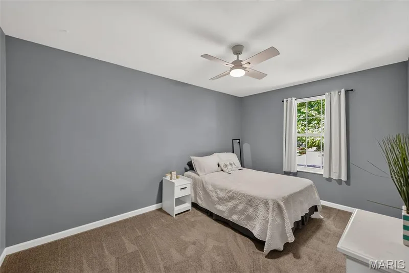 Carpeted room featuring a single window, white baseboards, and a ceiling fan with integrated lighting — 23 Crescent Woods Drive, St Peters, MO 63376