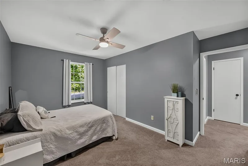 Spacious bedroom featuring soft gray walls, wood-finish flooring, and a ceiling fan with integrated lighting — 23 Crescent Woods Drive, St Peters, MO 63376