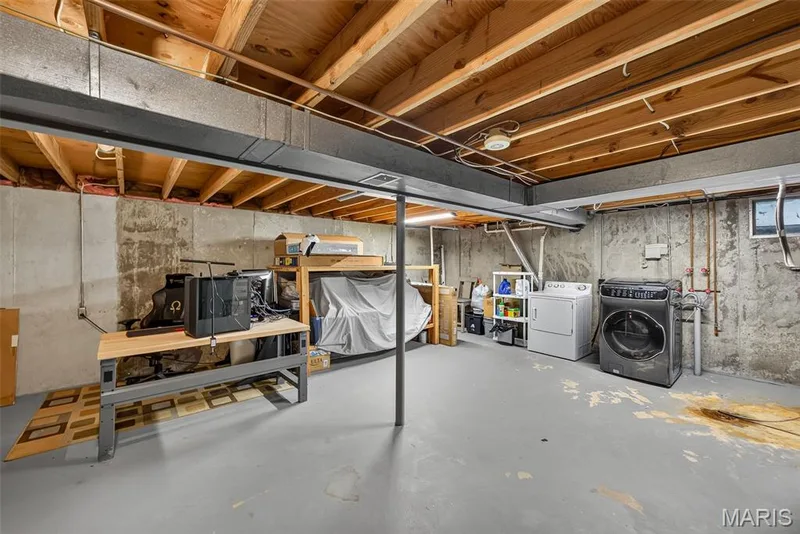 Versatile basement space featuring exposed wood-beam ceiling, steel support columns, and polished concrete flooring — 23 Crescent Woods Drive, St Peters, MO 63376