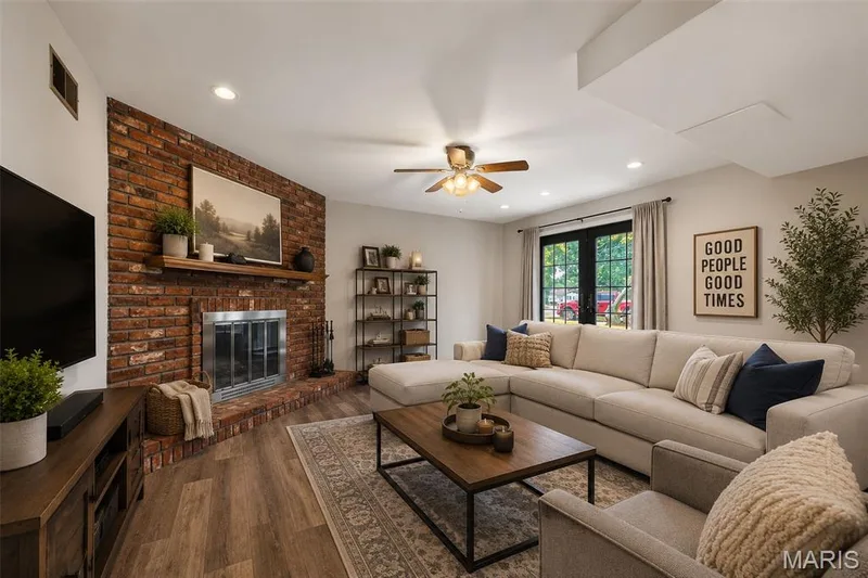 Bright living room showcasing a wood-burning fireplace with exposed brick surround, recessed ceiling lighting, and a ceiling fan — 1319 Brandywine Lane, St Peters, MO 63376