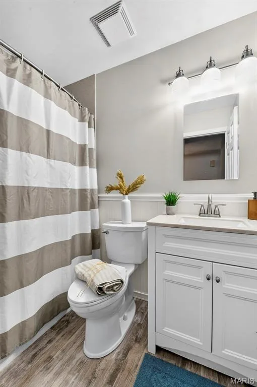Bathroom featuring wood-finish flooring, a white vanity with a light-colored countertop, and a vanity light fixture with three globes — 1319 Brandywine Lane, St Peters, MO 63376