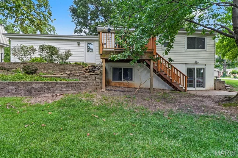 Rear exterior featuring a wooden deck with stairs, a patio, and dual-pane sliding glass doors — 1319 Brandywine Lane, St Peters, MO 63376