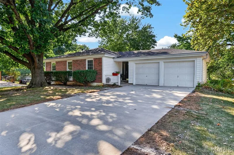 Brick and siding exterior with a two-car garage, concrete driveway, and mature landscaping — 1319 Brandywine Lane, St Peters, MO 63376