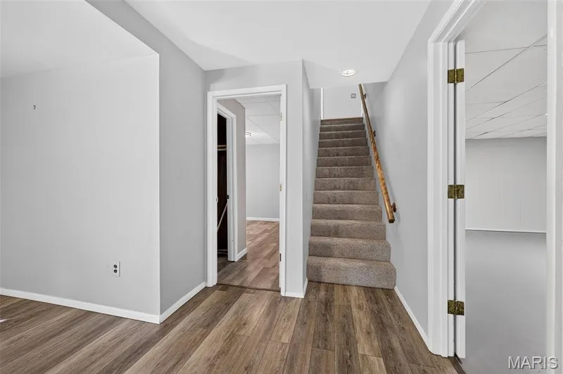 Wood-finish flooring, light grey wall paint, carpeted staircase, wood handrail, recessed lighting — 1319 Brandywine Lane, St Peters, MO 63376